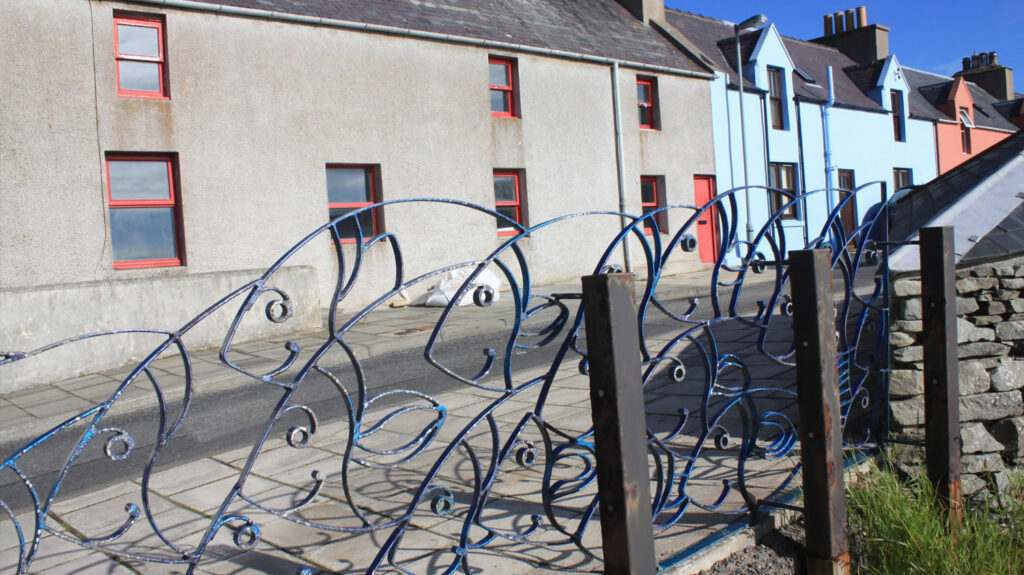 Fish Fence and colourful houses on New Street road, Scalloway