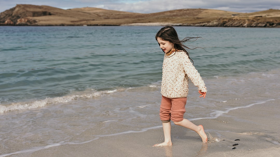 Young girl playing on a beach in Shetland